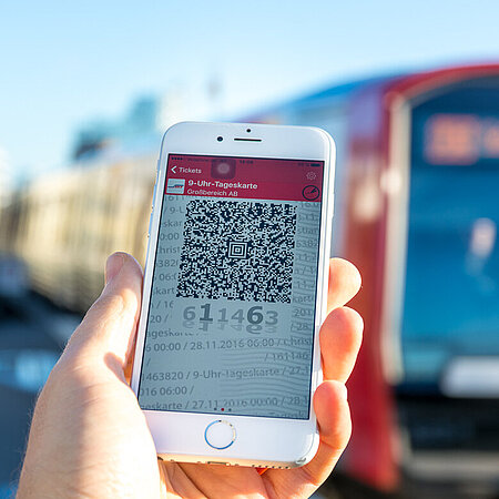HVV Apps QR-Code auf einem Smartphone Display im Hintergrund verschwommen eine Hamburg U-Bahn