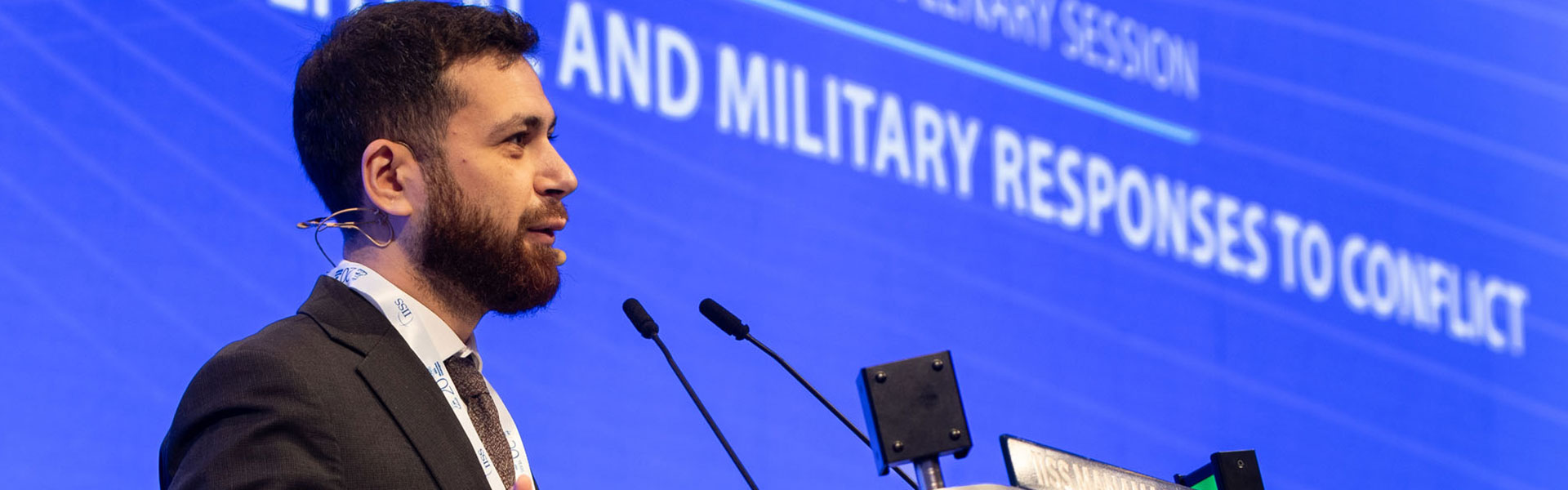 A conference header image showing a man in a suit speaking at a microphone in front of a blue GSIS backdrop.